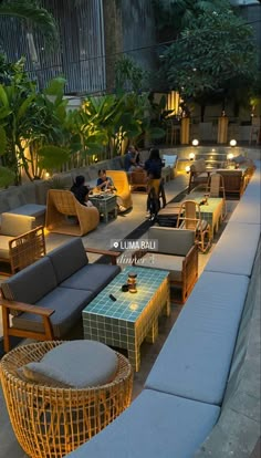 an outdoor seating area with wicker furniture and lights on the side walk at night