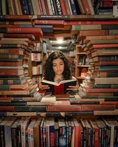 a woman reading a book while surrounded by books