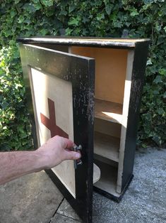 a hand is opening the door to a small cabinet that has been painted black and red