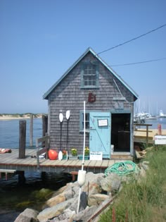 a boat dock with a small house on it's side and water in the background