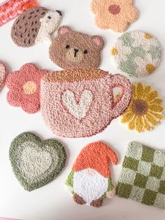 crocheted tea cozies with teddy bears and hearts on them are laid out