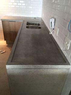 a kitchen counter with a sink in the middle and an electrical outlet plugged into the wall