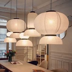 a room filled with lots of white lights hanging from it's ceiling above a dining table