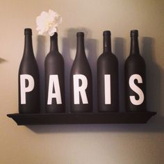 several black bottles with the word paris on them and a white flower in each one