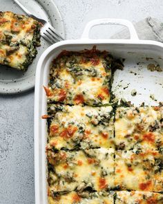 a casserole dish with spinach and cheese in it next to a fork