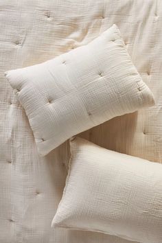 two white pillows sitting on top of a bed