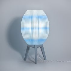 a blue and white lamp sitting on top of a wooden stand next to a gray wall