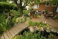 an outdoor garden with lots of plants and flowers on the ground, along with a wooden walkway