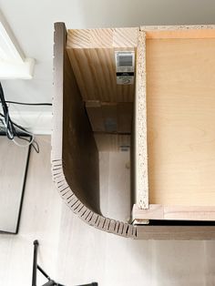 an overhead view of a wooden table with some wires on the wall and a chair in the background