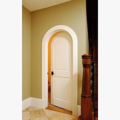 an arched doorway in a home with tile flooring and walls, along with a wooden door