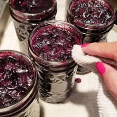 four jars of blueberry compote sitting on top of a white countertop