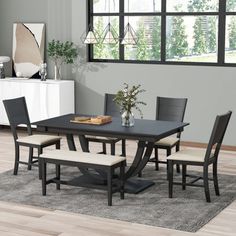 a dining room table with four chairs and a bench in front of the window,