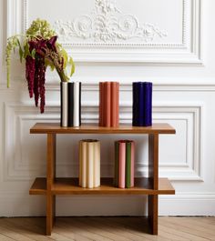 a wooden table topped with vases filled with flowers next to books on top of it