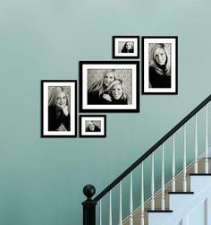 black and white photo frames hanging on the wall next to a stair case in a home