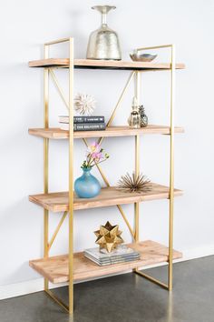 a shelf with books, vases and other items on it against a white wall