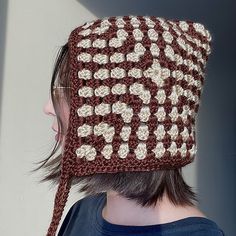 a woman wearing a brown and white crocheted hat