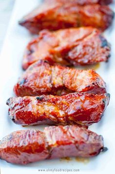 several pieces of meat are lined up on a white plate