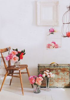 flowers are in vases next to an old suitcase and birdcage