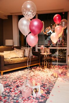 balloons and confetti are on the floor in front of a living room window