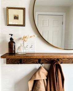 a mirror and coat hanger on a wall above a towel rack in a bathroom