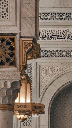 an ornate light fixture hanging from the side of a white wall with intricate carvings on it