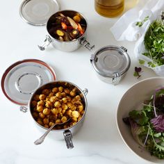 three bowls filled with food sitting on top of a white counter next to a salad