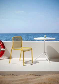 two yellow chairs and a white table on the beach