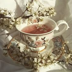 a tea cup and saucer filled with watermelon in front of white flowers