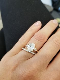 a woman's hand with a diamond ring on top of her finger and an engagement band