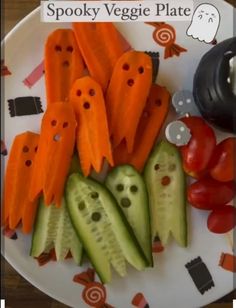 a plate topped with cucumbers and carrots cut in to shape ghost faces