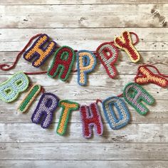 a happy birthday banner made out of crochet on a wooden background with the word happy written in large letters