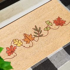 a door mat with leaves on it next to a potted plant and window sill