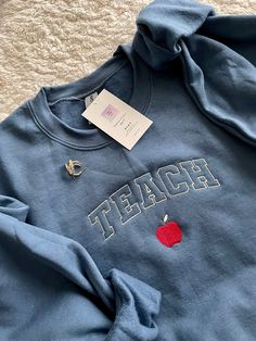 "The softest and coziest crewneck to hold you down this school year! Represent teacher life whether you're a teacher yourself or know a great teacher - this sweatshirt is perfect especially when personalized with their name!  Standard thread colors will come as seen in primary listing photos (creme yellow), if you'd like to change the thread colors, please list in the personalization box.  *Please note: if you like the pink option as seen in listing photo on gray sweatshirt, just list \"PINK OPT Crikit Ideas, Teacher Appropriate Outfits, Teach Sweatshirt, Teacher Fits, Cute Teacher Outfits, Teacher Accessories, Teacher Vibes, Teacher Aesthetic, Teaching Outfits