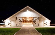 a barn at night with lights on the front door and side doors open to let people know where they are going