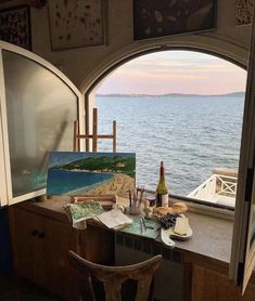 an artist's desk in front of a window overlooking the water