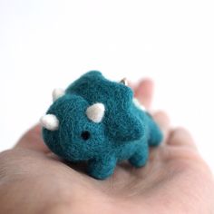 a hand holding a tiny stuffed animal in it's palm