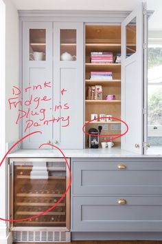 a kitchen with white cabinets and red marker writing on the glass doored cabinet doors