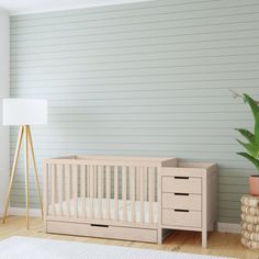 a baby crib next to a potted plant in a room with white walls