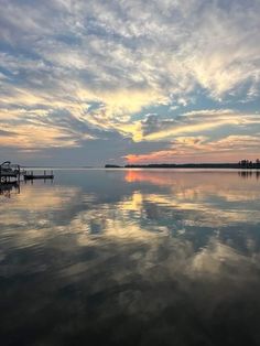 the sky is reflected in the calm water at sunset, with clouds reflecting on the water