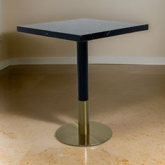 a black and gold square table sitting on top of a tile floor next to a window