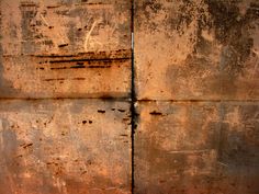 an old rusted metal wall with two pieces of paint peeling off the top and bottom