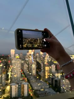 a person holding up a cell phone in front of a cityscape