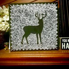 a paper cut out of a deer on top of a wooden shelf next to flowers