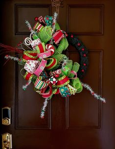 a christmas wreath is hanging on the front door with candy canes and ribbons attached to it