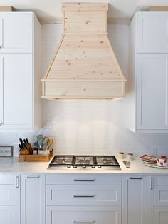 a stove top oven sitting inside of a kitchen under a wooden hood over it's burner