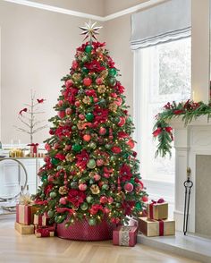 a decorated christmas tree in a living room with red and green ornaments on the top