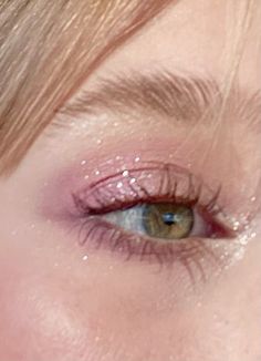 a woman's eye with pink glitter on the lashes and under her eyes is looking at the camera