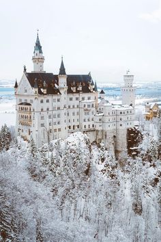 an old castle is surrounded by snow covered trees