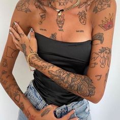 a woman with lots of tattoos on her arm and chest, holding something in her hand