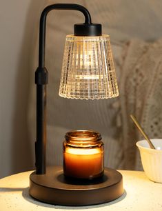 a lit candle sits on a table next to a jar with a light in it